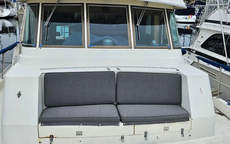 Slide: The Image of 1976 Hatteras 48 LRC yacht with cushioned seating at the stern, docked in a marina. - 4