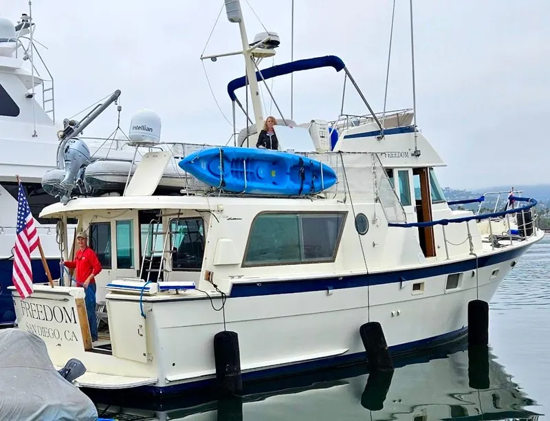 Slide: The Image of 1976 Hatteras 48 LRC yacht docked with blue kayak and American flag. - 5