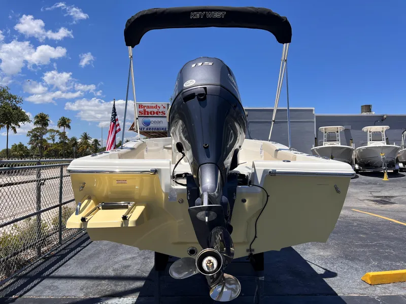 Slide: The Image of 2025 Key West 179 FS boat with outboard motor, parked outdoors under clear blue sky. - 4