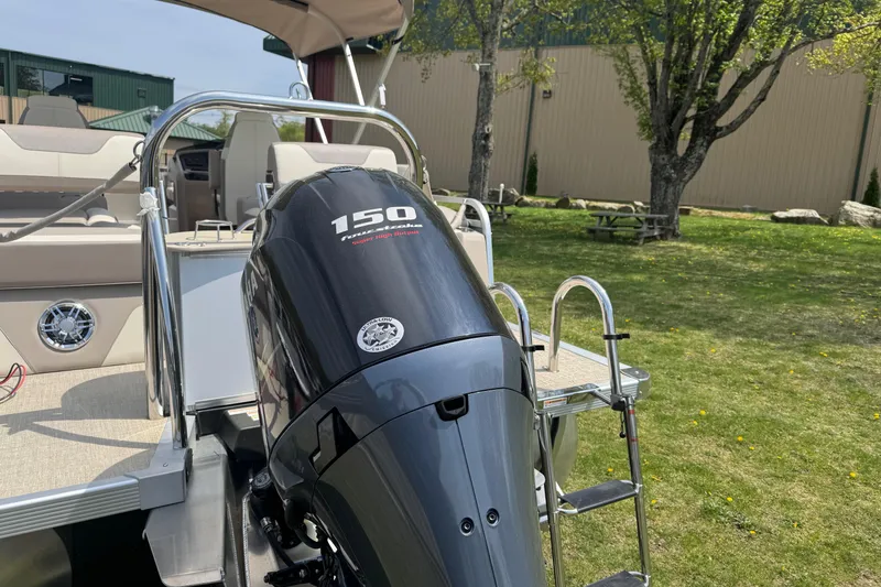 Slide: The Image of 2025 Tahoe Pontoon LTZ Quad Lounger Shift with powerful 150 horsepower engine, parked outdoors. - 18