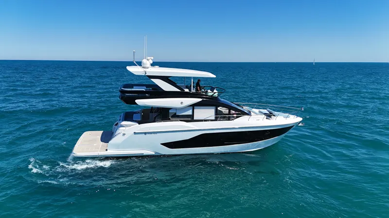 Slide: The Image of The 2026 Cruisers Yachts 57 Fly cruises on calm, blue waters under a clear sky. - 7