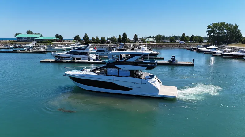 Slide: The Image of A luxurious motor yacht with a sleek design cruises through a calm harbor with several boats. - 1