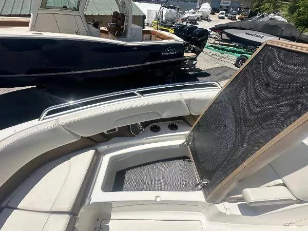 Slide: The Image of 2014 Chaparral 307 SSX boat interior with seating and storage, docked near other boats. - 16