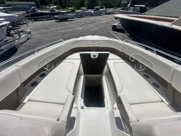 Slide: The Image of 2014 Chaparral 307 SSX boat interior with spacious seating and storage, docked in a marina. - 17