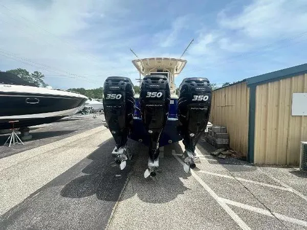 Slide: The Image of 2018 Scout 350 LXF boat with triple outboard engines in a marina setting. - 4
