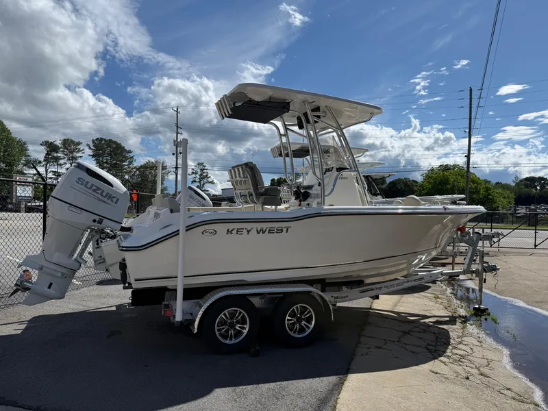 Slide: The Image of 2025 Key West 219 FS boat on trailer with Suzuki outboard motor, parked outdoors. - 2