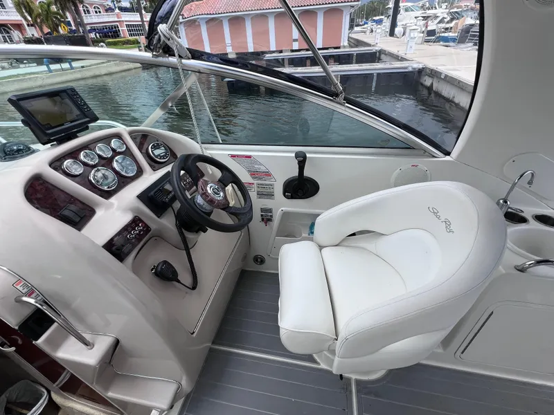 Slide: The Image of 2004 Sea Ray 260 Sundancer helm with steering wheel, gauges, and white captain's chair. - 15