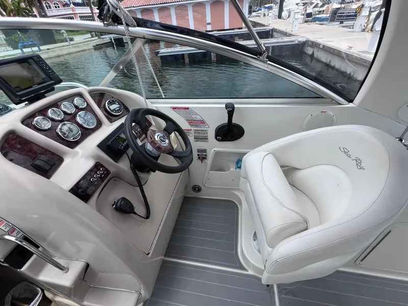 Slide: The Image of 2004 Sea Ray 260 Sundancer helm with steering wheel and captain's chair by the water. - 16