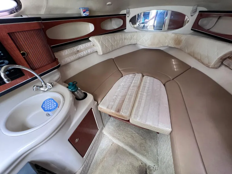 Slide: The Image of 2004 Sea Ray 260 Sundancer cabin interior with seating, sink, and wooden accents. - 22