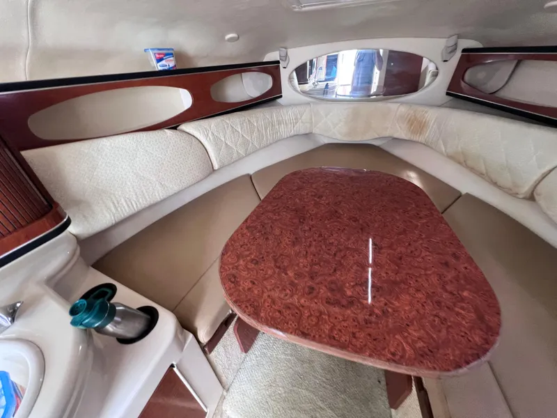 Slide: The Image of Interior cabin of 2004 Sea Ray 260 Sundancer with wood table and beige seating. - 23