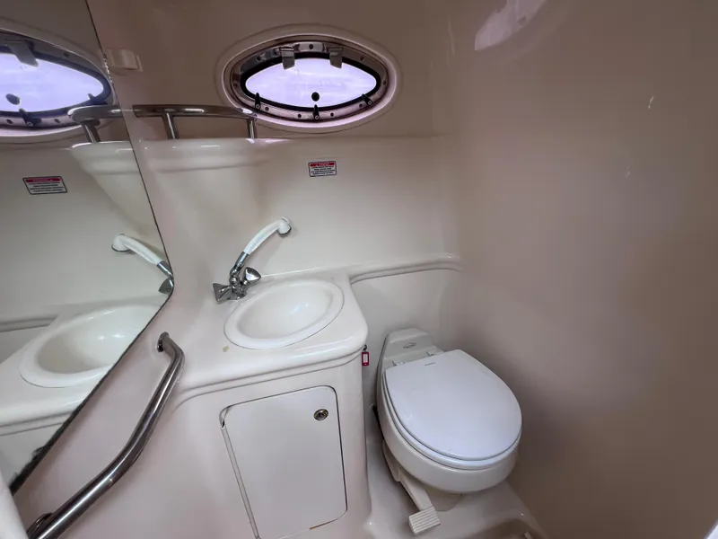 Slide: The Image of 2004 Sea Ray 260 Sundancer bathroom with sink, toilet, and porthole window. - 26