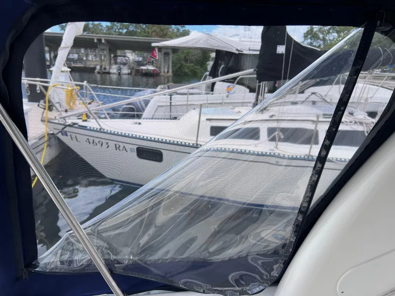 Slide: The Image of 2004 Sea Ray 260 Sundancer with mesh cover, docked near other boats. - 29