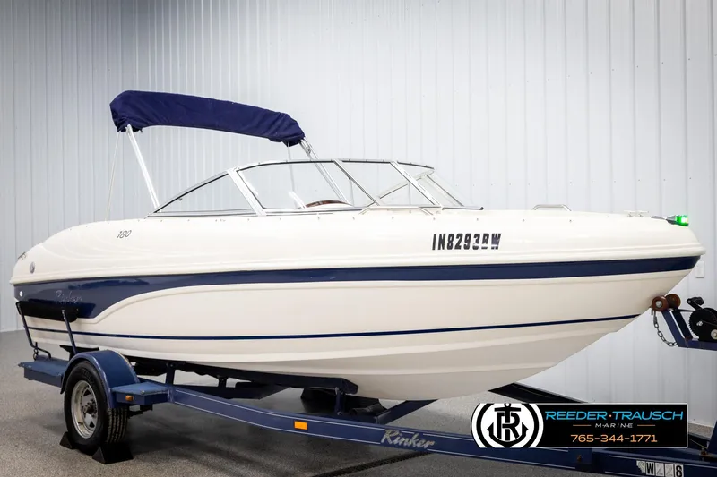 Slide: The Image of 2002 Rinker 180 boat on trailer with blue canopy, displayed indoors. - 1