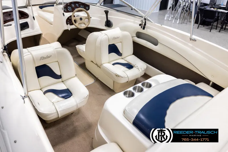 Slide: The Image of 2002 Rinker 180 boat interior with white and blue seating, steering wheel, and cup holders. - 10