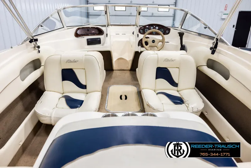 Slide: The Image of 2002 Rinker 180 boat interior with cream and blue seating, steering wheel, and dashboard. - 12