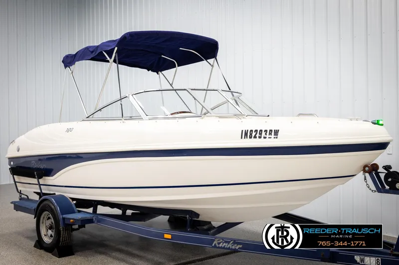 Slide: The Image of 2002 Rinker 180 boat with blue canopy on trailer in showroom. - 2