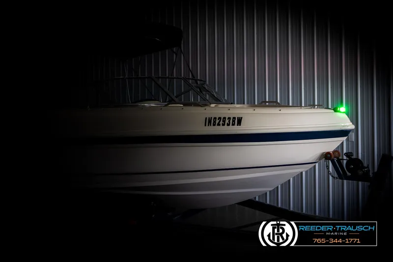 Slide: The Image of 2002 Rinker 180 boat in dimly lit storage, side view with visible registration number. - 3