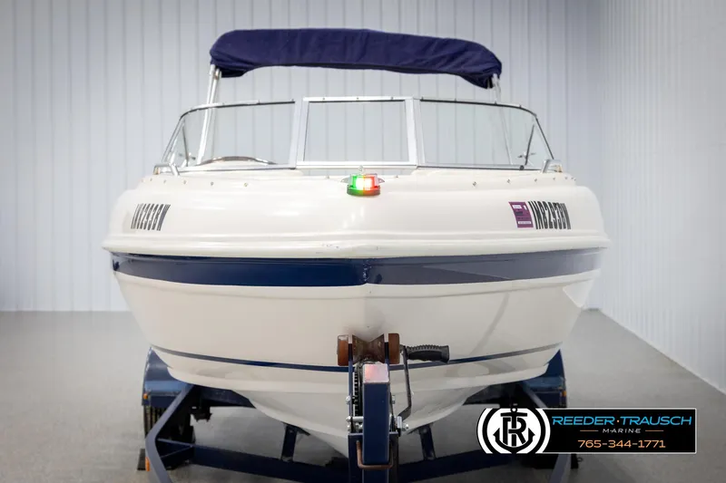 Slide: The Image of 2002 Rinker 180 boat with blue canopy on trailer in indoor showroom. - 7
