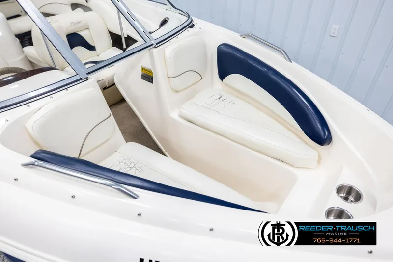 Slide: The Image of 2002 Rinker 180 boat interior with white and blue seating, cup holders, and windshield. - 8