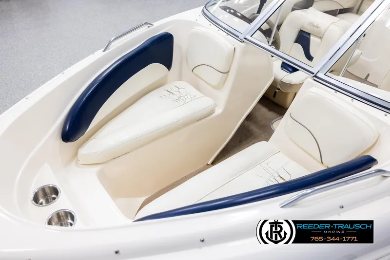 Slide: The Image of 2002 Rinker 180 boat interior with white and blue seating, cup holders, and windshield. - 9