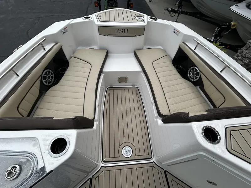 Slide: The Image of 2023 Yamaha Boats 255 FSH Sport E interior with beige seating and speakers. - 2