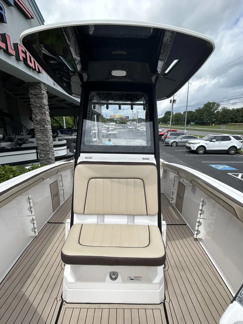 Slide: The Image of 2023 Yamaha Boats 255 FSH Sport E, center console view, beige seating, outdoor display. - 6
