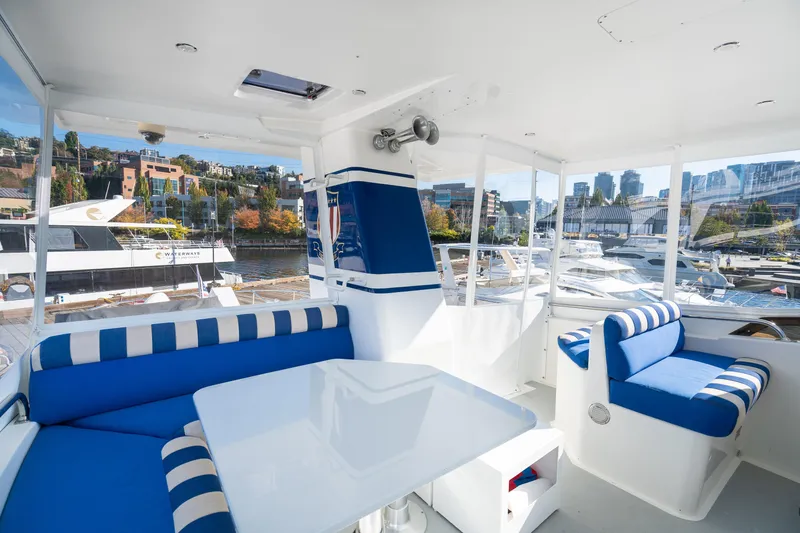 Slide: The Image of Interior of a 1998 Northern Marine Trawler with blue and white seating, docked at a marina. - 52