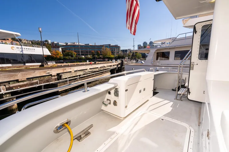 Slide: The Image of 1998 Northern Marine Trawler docked, featuring spacious deck and American flag, under clear blue sky. - 7