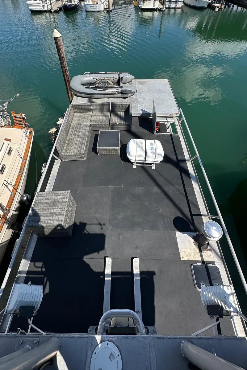 Slide: The Image of Custom 2002 Carlson Marine Trawler docked, featuring spacious deck and moored boats in background. - 34