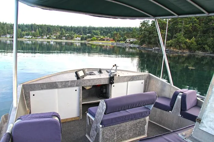 Slide: The Image of 2002 Carlson Marine Trawler interior with seating, overlooking serene water and forested shoreline. - 48