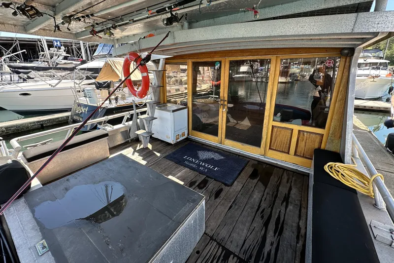 Slide: The Image of Custom 2002 Carlson Marine Trawler docked, featuring wooden doors, seating, and nautical equipment. - 6