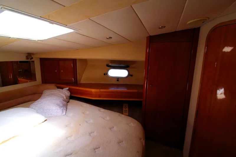 Slide: The Image of 1997 Viking Sport Cruisers 48SC cabin interior with bed, wooden cabinetry, and porthole window. - 15