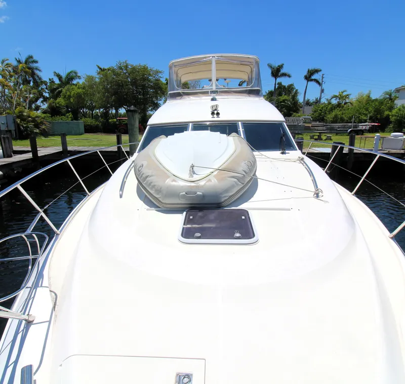 Slide: The Image of 1997 Viking Sport Cruisers 48SC yacht with inflatable boat on deck, docked under clear blue sky. - 20