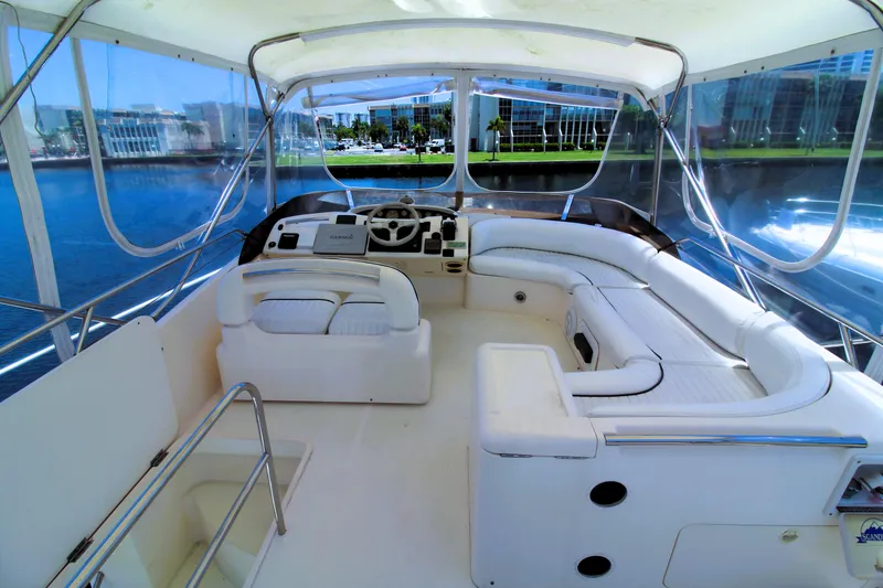 Slide: The Image of 1997 Viking Sport Cruisers 48SC yacht interior with white seating and helm, docked by waterfront buildings. - 4