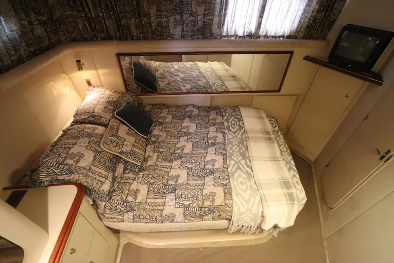 Slide: The Image of 1999 Cruisers Yachts 3750 Motoryacht bedroom with patterned bedding and a small TV. - 43
