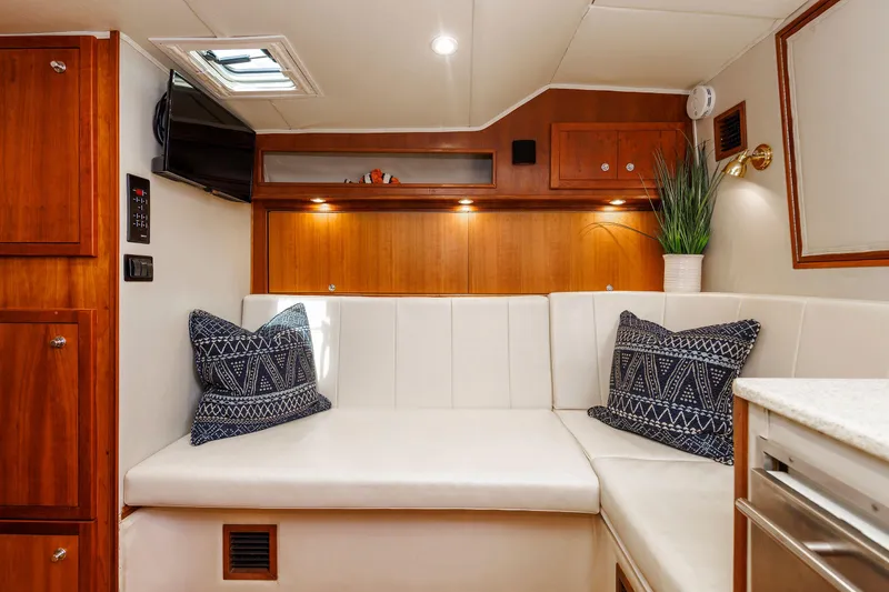 Slide: The Image of 2002 Albemarle 41 Express Fisherman cabin with white seating, wooden accents, and decorative pillows. - 33