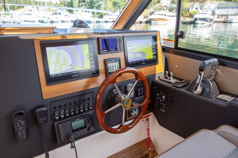 Slide: The Image of Helm of 2025 Cutwater 32 Coupe with dual navigation screens and wooden steering wheel. - 12