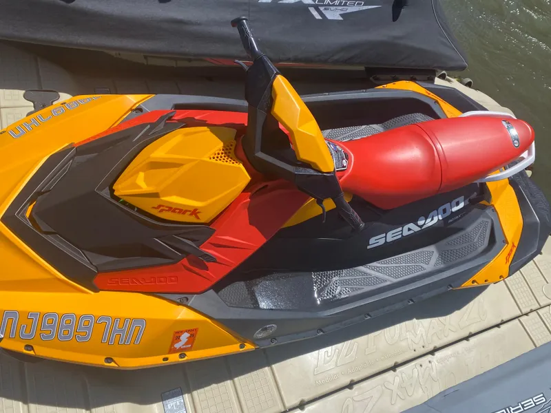 Slide: The Image of 2022 Sea-Doo Spark 3up jet ski in vibrant orange and red on a dock. - 3
