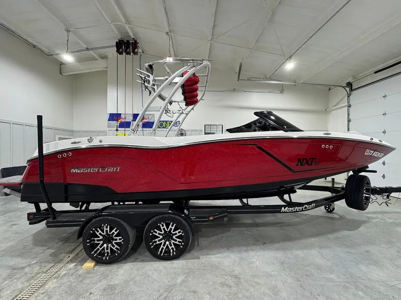Slide: The Image of 2016 MasterCraft NXT22 boat in a garage, red and white design, on a trailer. - 5