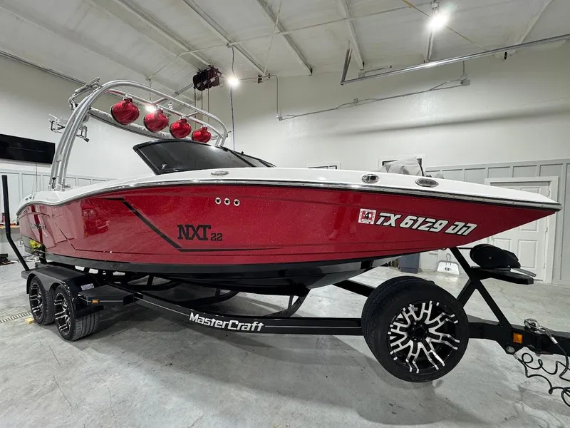 Slide: The Image of 2016 MasterCraft NXT22 boat in a showroom, red exterior, on a trailer. - 6