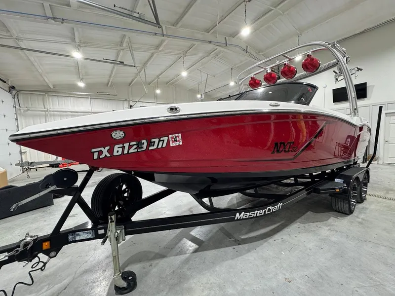 Slide: The Image of 2016 MasterCraft NXT22 boat in a garage, red and white exterior, on a trailer. - 7