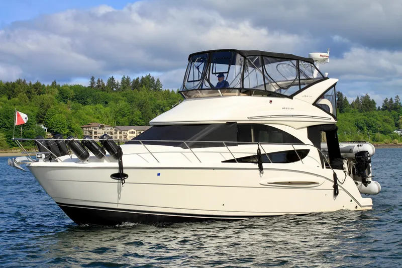 Slide: The Image of 2006 Meridian 341 Sedan yacht cruising on a scenic lake with lush green shoreline. - 0