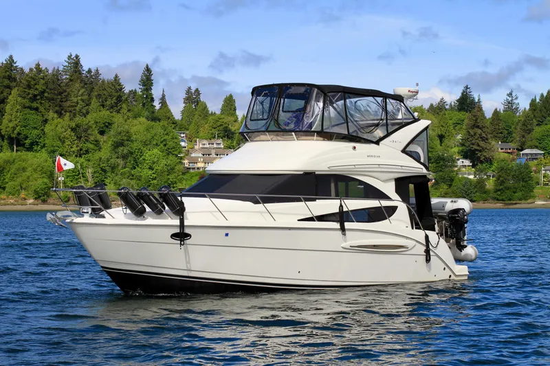 Slide: The Image of 2006 Meridian 341 Sedan yacht on a serene lake with lush green forest backdrop. - 2