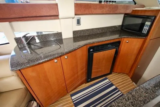 Slide: The Image of 2006 Meridian 341 Sedan yacht kitchen with granite countertops, sink, microwave, and mini fridge. - 42