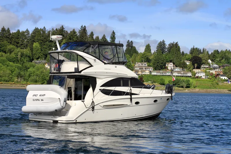 Slide: The Image of 2006 Meridian 341 Sedan yacht cruising on a scenic lake with lush greenery and houses in the background. - 5