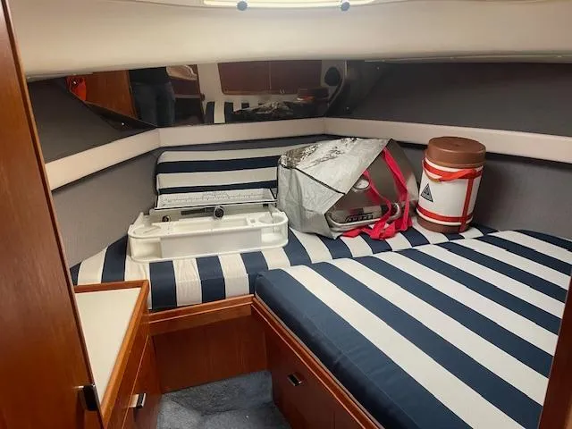 Slide: The Image of 1990 Tiara Yachts 3100 Open cabin with striped bedding and storage items. - 10