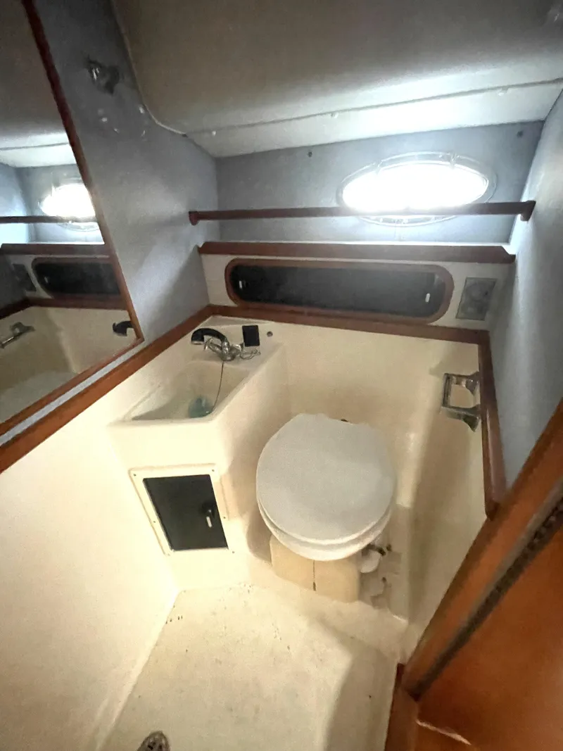 Slide: The Image of 1990 Tiara Yachts 3100 Open bathroom with sink, toilet, and porthole window. - 14