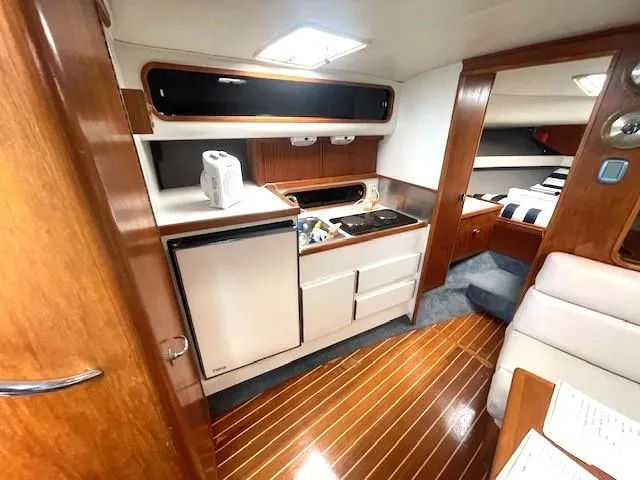 Slide: The Image of 1990 Tiara Yachts 3100 Open interior with kitchenette, wood flooring, and cozy cabin space. - 7