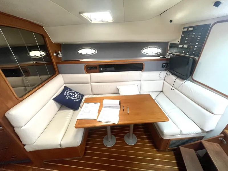 Slide: The Image of 1990 Tiara Yachts 3100 Open interior with white seating, wooden table, and nautical decor. - 8