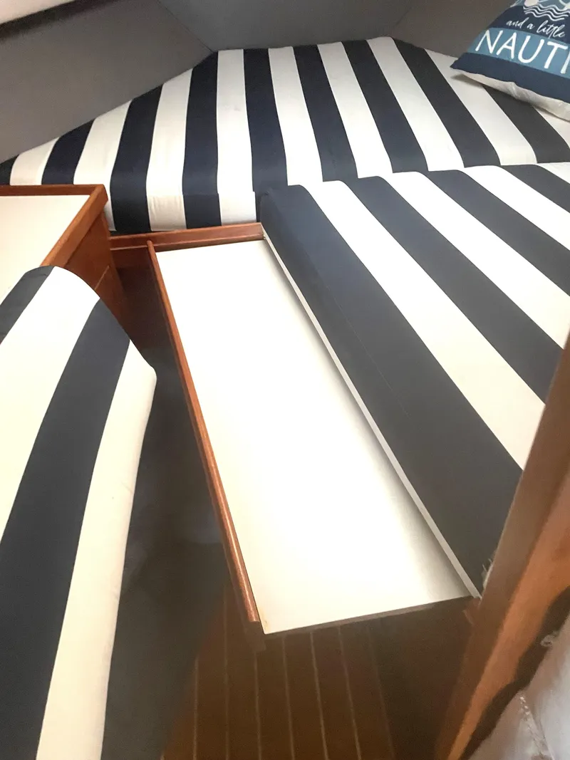 Slide: The Image of 1990 Tiara Yachts 3100 Open cabin with striped cushions and wooden storage drawers. - 9